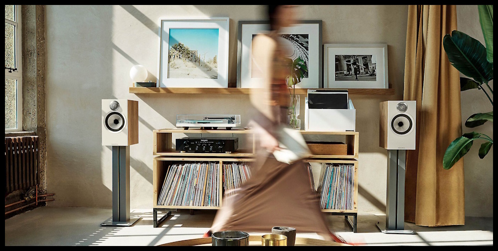 Bowers & Wilkins 606 S3 hoparlör, aydınlık oturma odasında plak dolabı yanında.
